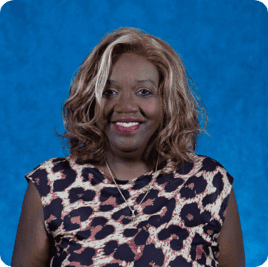 Smiling woman with curly hair wearing a leopard print top against a blue background.