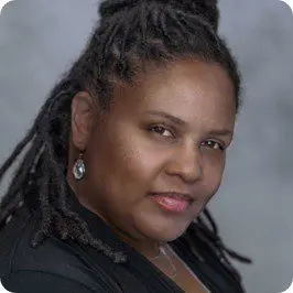 Professional portrait of a woman with braided hair and earrings.