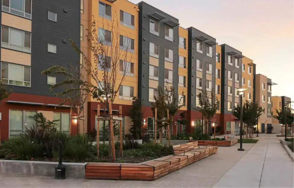 Modern apartment complex with landscaped courtyard and benches.