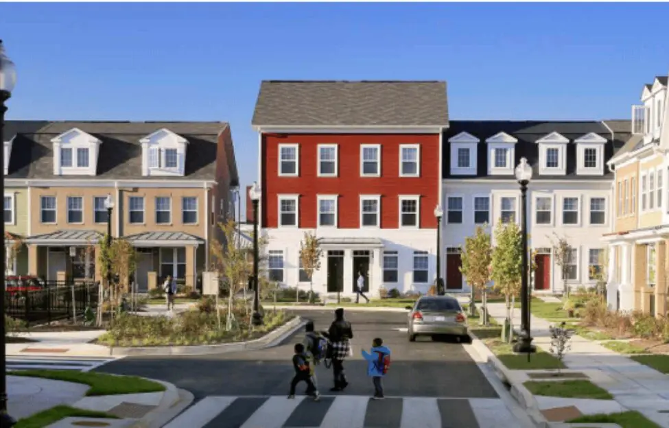 Row of colorful modern townhouses with people walking on the sidewalk.